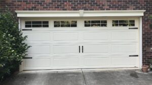 A white garage door with decorative hardware on a brick house by Total Garage Works in Indian Trail, NC.