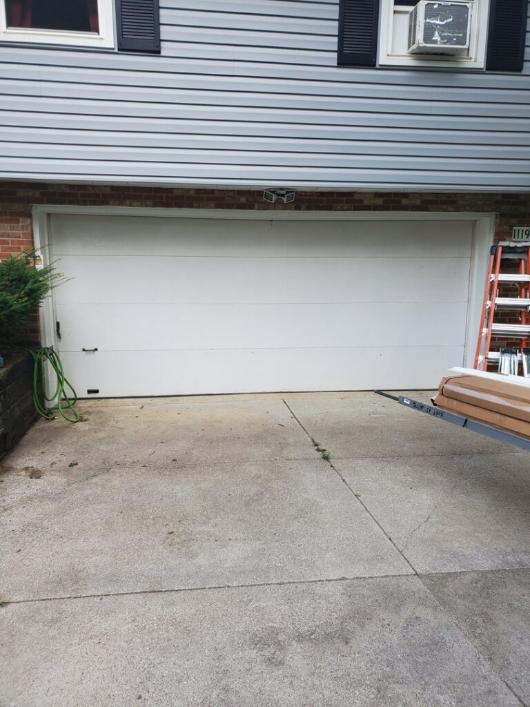 A white garage door installation site with a ladder and materials, by Lucas Overhead Doors in Erie, PA.