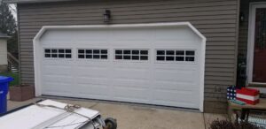 A white garage door with windows and materials on site, installed by Lucas Overhead Doors in Erie, PA.