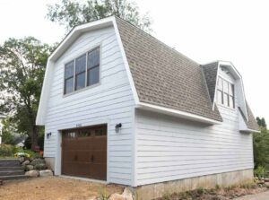 A remodeled white garage exterior with a brown door and gambrel roof, by Northrup Remodeling in Minneapolis, MN