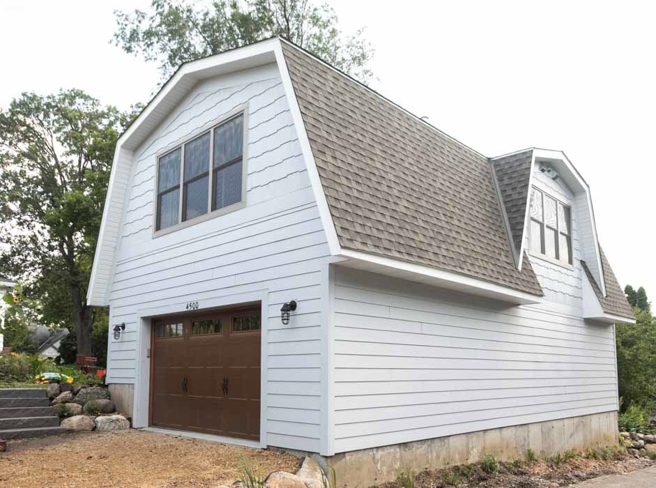 A remodeled white garage exterior with a brown door and gambrel roof, by Northrup Remodeling in Minneapolis, MN