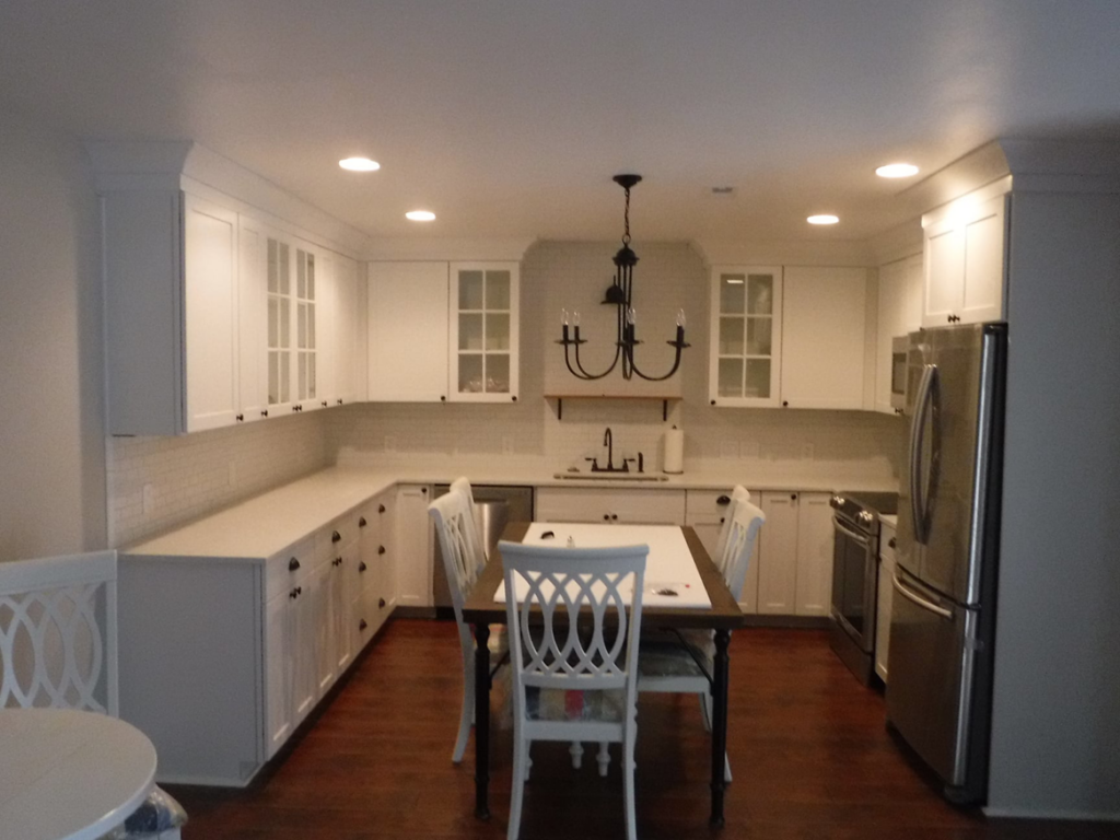 A newly remodeled kitchen featuring white cabinets and stainless steel appliances by Husbands On Call in Virginia Beach, VA.