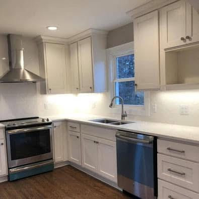 A newly installed kitchen with white cabinets, stainless steel appliances, and a modern sink, completed by Orion Construction Services in Duluth, MN.