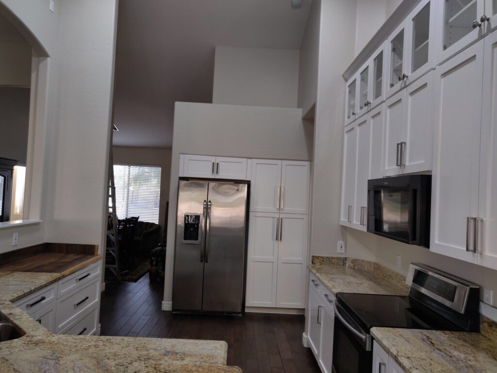 Spacious kitchen with white cabinets, granite countertops, and a stainless steel refrigerator by Camelback Cabinets in Gilbert, AZ