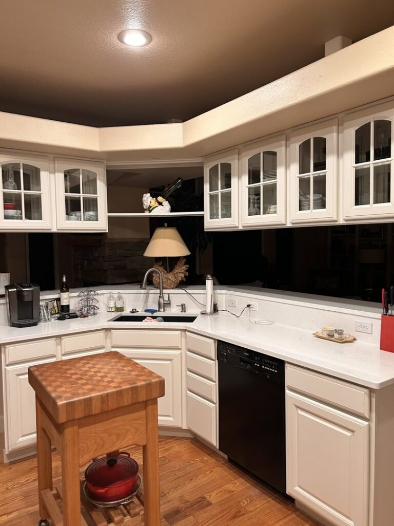 A modern white kitchen with a dark backsplash and a wooden island by Greg Unseth Painting & Exteriors in Colorado Springs, CO