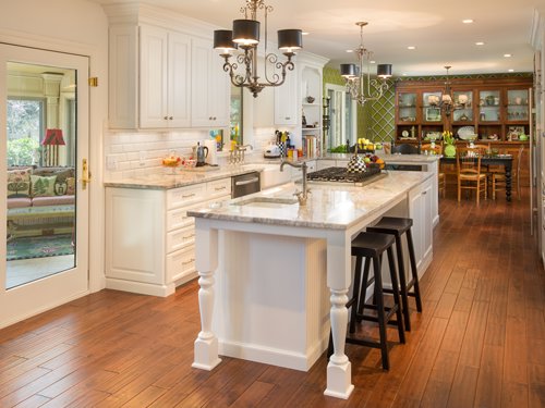 A bright white kitchen featuring a large island with dark stools by Saunders Dynamic Remodeling in Columbus, OH