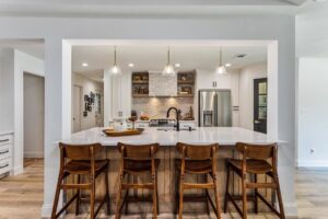 A renovated kitchen featuring white cabinets, a large range hood, and stainless steel appliances by DFW Improved in Plano, TX.