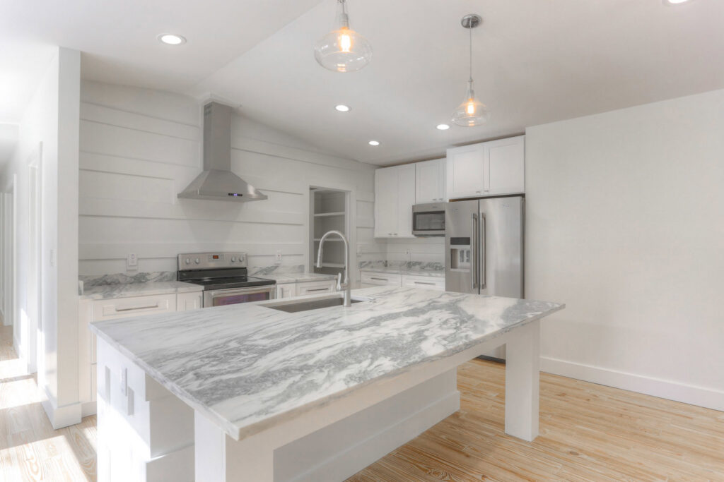 A bright white kitchen featuring elegant marble countertops and a spacious island, completed by Pioneer Built in St. Petersburg, FL.