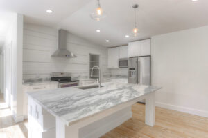 A bright white kitchen featuring elegant marble countertops and a spacious island, completed by Pioneer Built in St. Petersburg, FL.