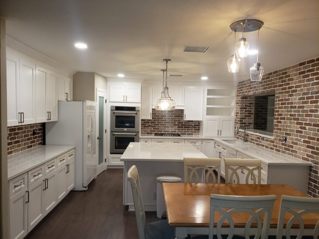 A bright kitchen remodel with white cabinets, a brick backsplash, and a large island by LJ Builders in Chandler, AZ