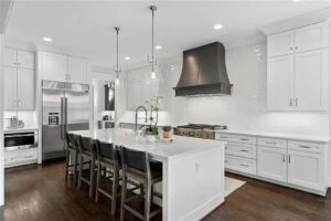 A bright white kitchen remodel with a large island and stainless steel appliances by Inland Home Remodeling Inc. in Chicago, IL.