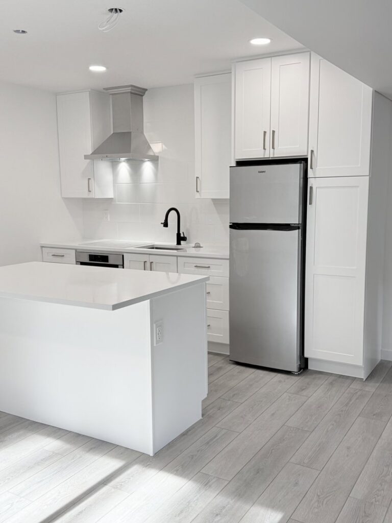 A bright, newly remodeled kitchen with white cabinets, a central island, and new flooring by JP. Remodel Service LLC in Everett, WA.