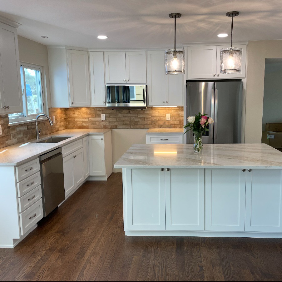 A white kitchen remodel with wood floors and a large island by Alpine Contracting in Colorado Springs, CO