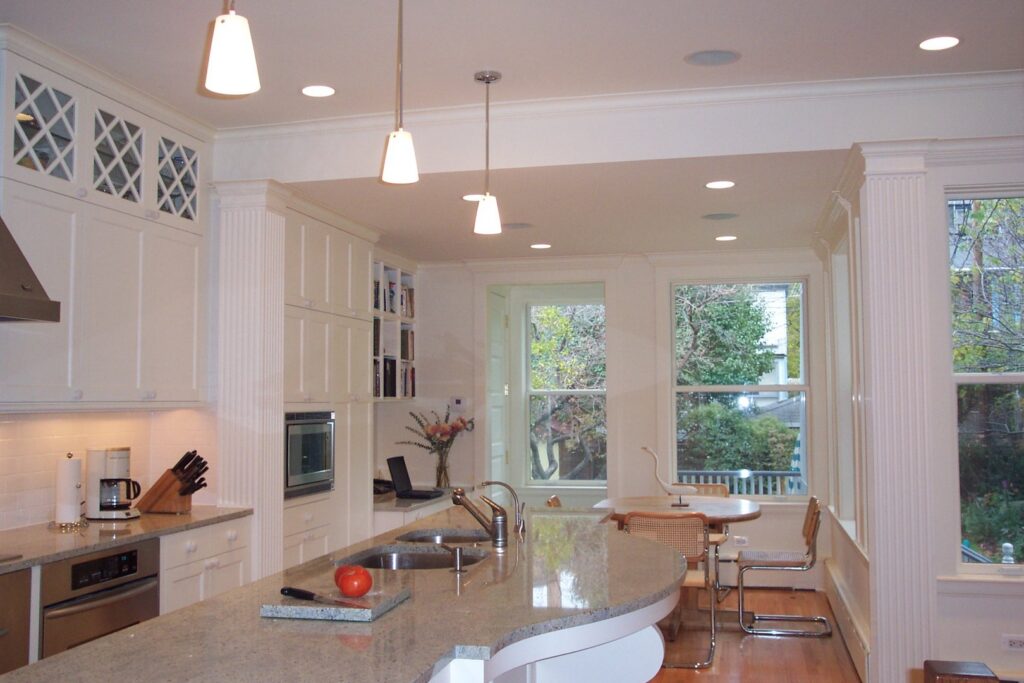A renovated kitchen with white cabinets, granite countertops, and a large island by S.N. Peck Builder, Inc. in Chicago, IL.