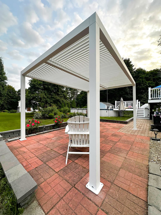 A newly installed white louvered pergola on a brick patio by Vlad's Handyman Services in Manchester, NH.