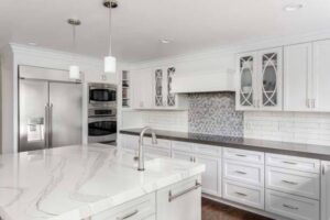 A kitchen featuring a large island with a white marble-patterned countertop and white cabinets installed by Counter Fitters in Savannah, GA