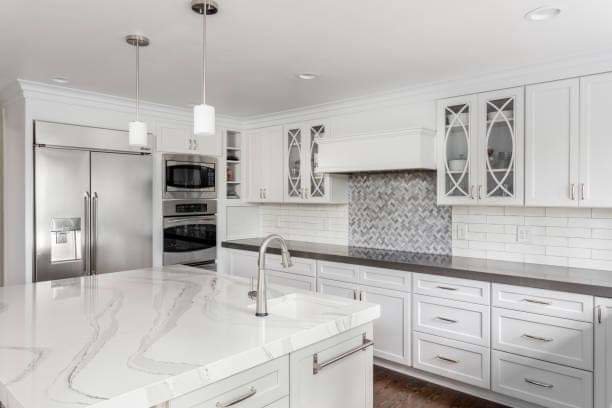 A kitchen featuring a large island with a white marble-patterned countertop and white cabinets installed by Counter Fitters in Savannah, GA