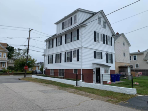 A white multi-story house exterior with a newly installed or painted fence by D'Costa Finish Painting in Fall River, MA.