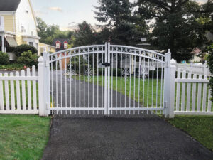 Beautiful white ornate metal gate with matching picket fences installed by National Fence Systems, Inc. in Avenel, NJ.