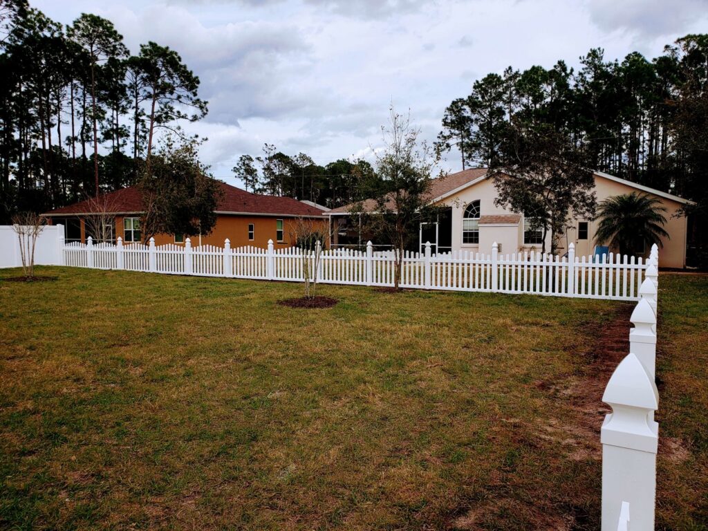 A white picket fence installed around a residential backyard by NGC FENCE INC in Jacksonville, FL.