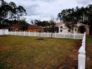 A white picket fence installed around a residential backyard by NGC FENCE INC in Jacksonville, FL.