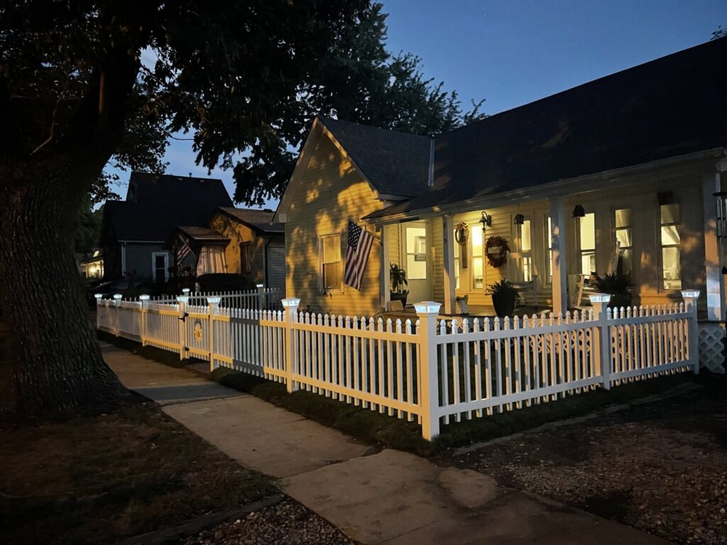 A newly installed white picket fence with solar lights around a house by Smitty's Handyman Service LLC in Mesquite, TX.