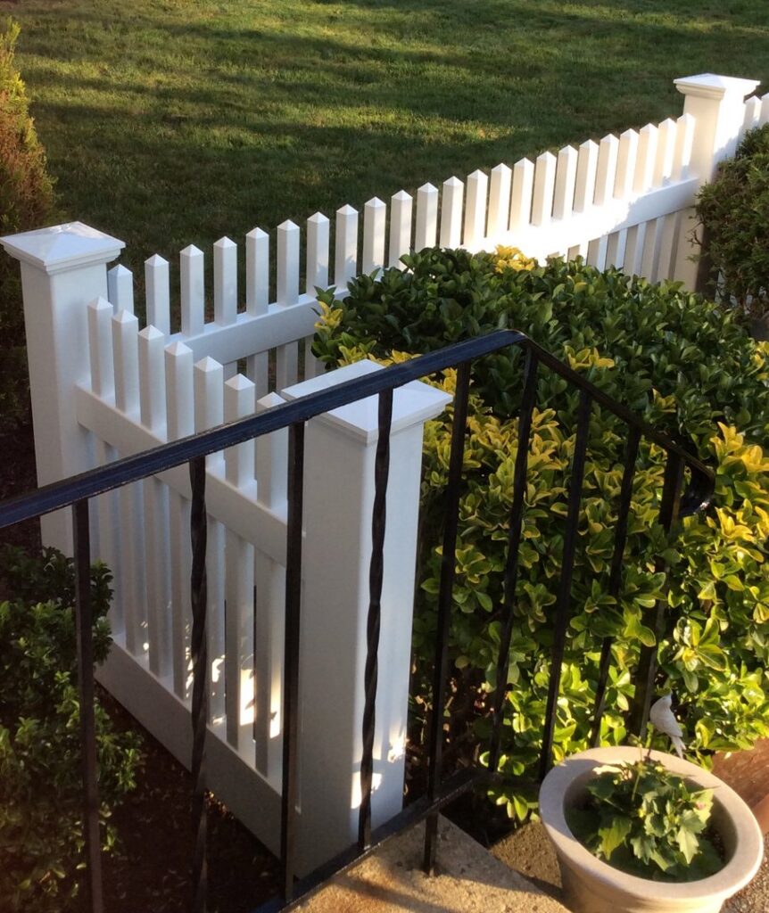 A section of white picket fence complementing a black metal railing, installed by Fence Factory Inc in Stamford, CT