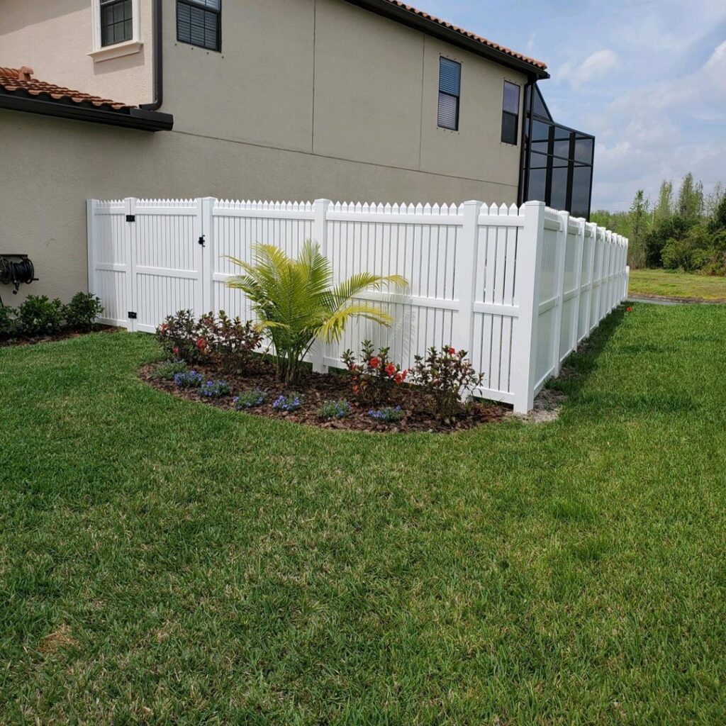 A classic white picket-style vinyl fence installed around a residential yard by Keeler Fence in New Port Richey, FL.