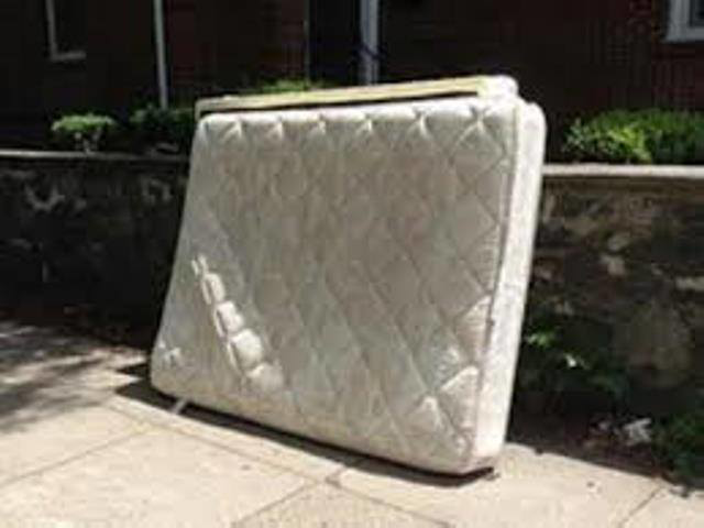 A white quilted mattress placed on a sidewalk for disposal by Omaha junk Removal and Hauling Service in Omaha, NE.