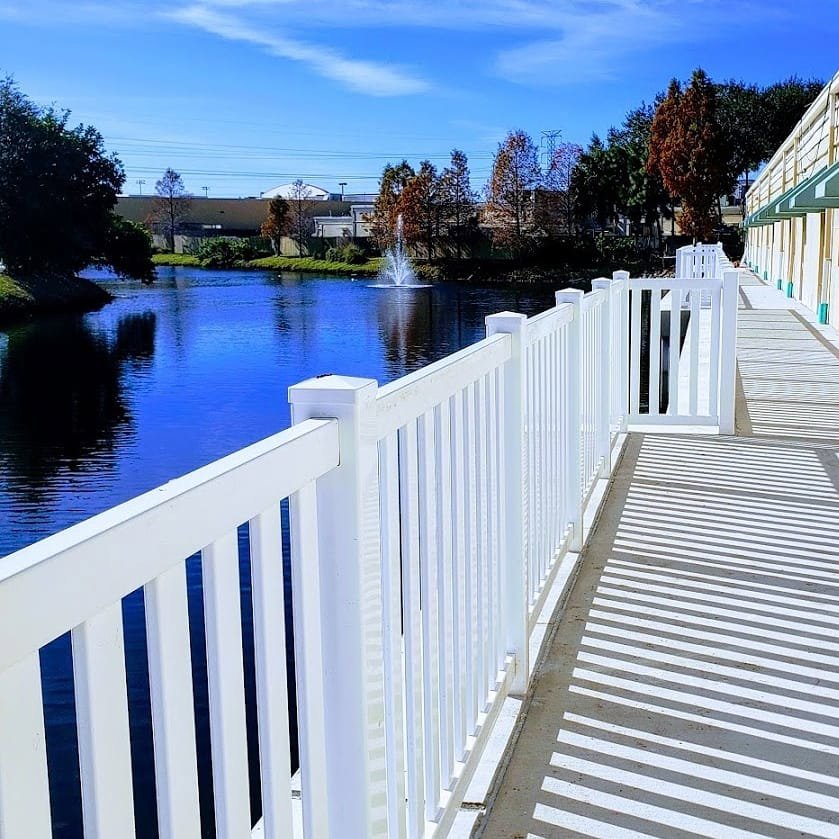 A newly installed white railing along a walkway next to a pond by Keeler Fence in New Port Richey, FL.