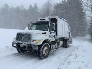 A white rubbish collection truck from Reed & Sons Rubbish on a snowy road in Guilford, VT, ready for junk removal.