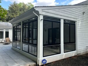 A modern sunroom addition with white siding and black window frames by X-Terior Techs in Henrico, VA.
