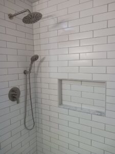 White subway tile shower installation with a built-in niche by APS Residential Services in Livonia, MI.