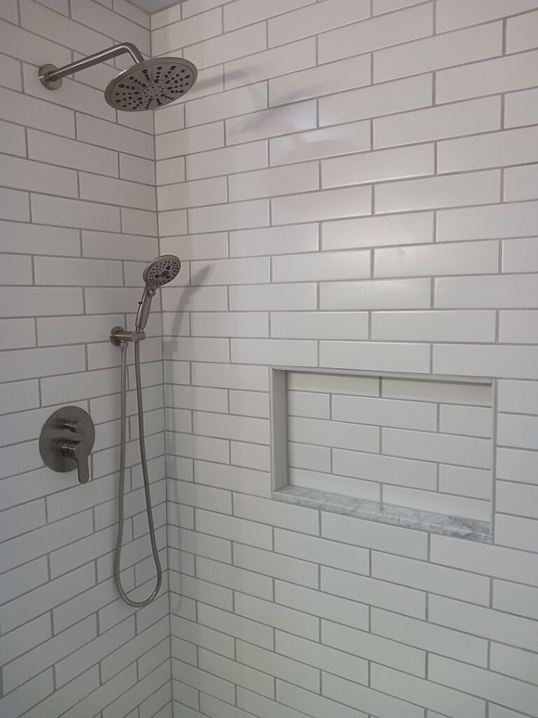 White subway tile shower installation with a built-in niche by APS Residential Services in Livonia, MI.