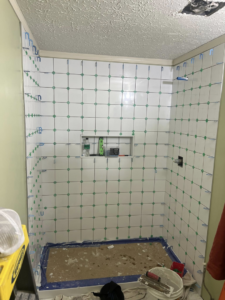 White tiles being installed on shower walls with spacers during a renovation by Home Changes in Knoxville, TN