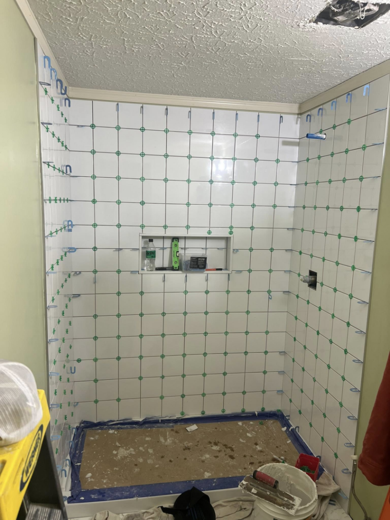 White tiles being installed on shower walls with spacers during a renovation by Home Changes in Knoxville, TN