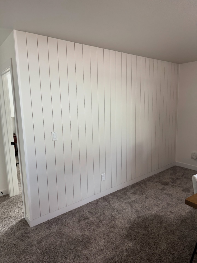 A newly installed white vertical shiplap accent wall by LIV Custom Accents in West Fargo, ND