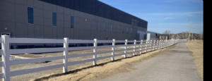 A newly installed white vinyl fence running alongside a commercial building by Aaron Fence in Tulsa, OK.