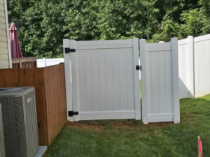 A newly installed white vinyl fence gate positioned next to an outdoor AC unit by S&L Decking and Fencing in Charlotte, NC.