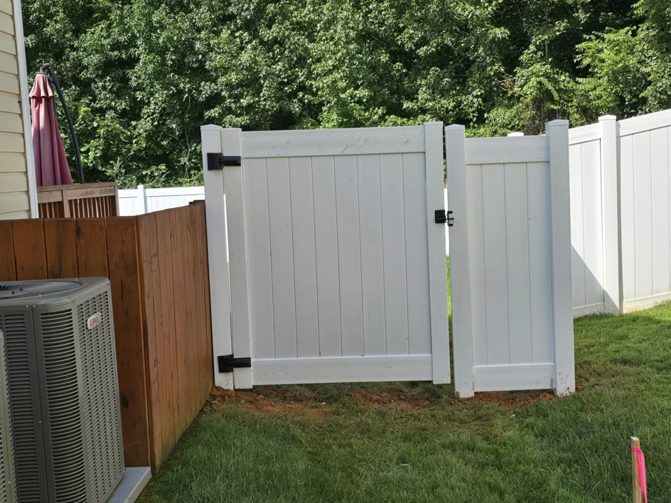 A newly installed white vinyl fence gate positioned next to an outdoor AC unit by S&L Decking and Fencing in Charlotte, NC.