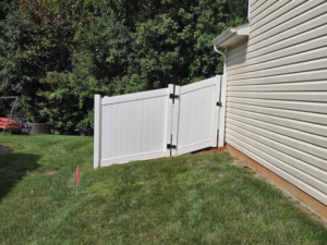 A newly installed white vinyl fence gate next to a residential house by S&L Decking and Fencing in Charlotte, NC.
