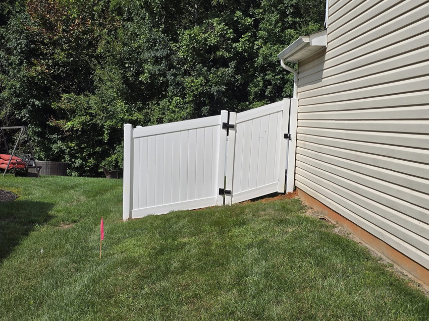 A newly installed white vinyl fence gate next to a residential house by S&L Decking and Fencing in Charlotte, NC.