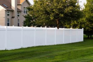 A newly installed white vinyl fence in a residential backyard by Eagle Exteriors in Cumberland, RI.