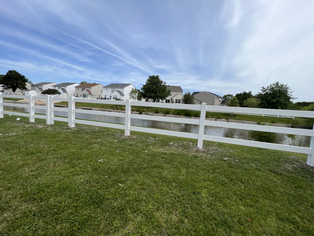 Newly installed white vinyl fence along a waterfront property by BOS HOME Exterior Services in Virginia Beach, VA