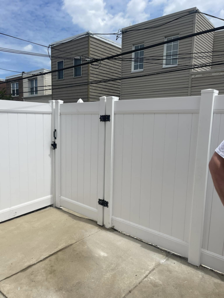 A newly installed white vinyl fence with a gate in a backyard by AC Fence and Ironworks in Philadelphia, PA.