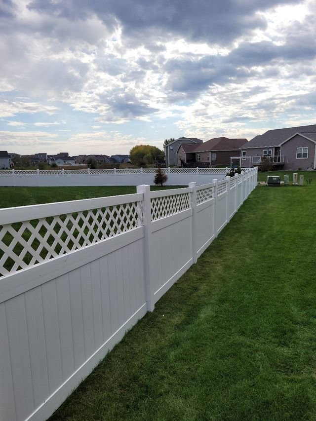 A white vinyl fence with a lattice top installed in a backyard, showing a longer view, by Badger Vinyl Products in Madison, WI.