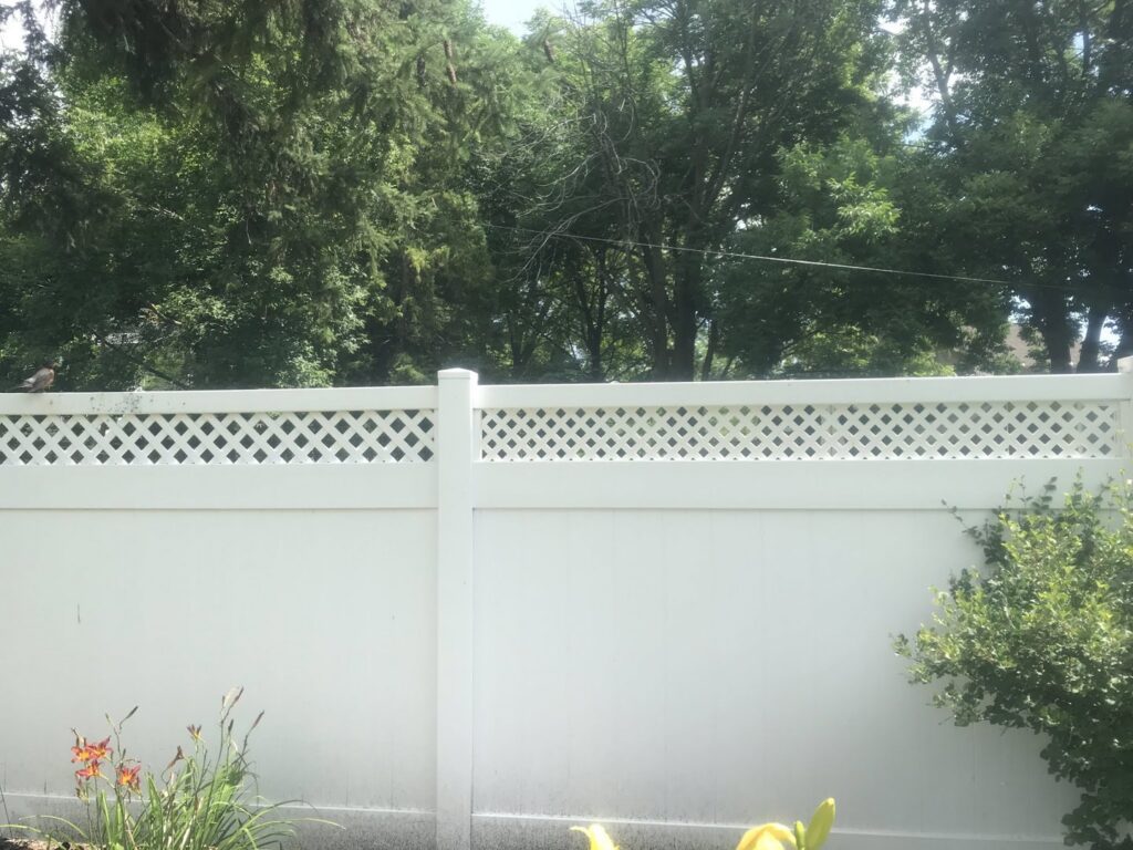 A white vinyl fence with a decorative lattice top installed in a backyard by A to Z Quality Fencing and Structures-Appleton, WI.