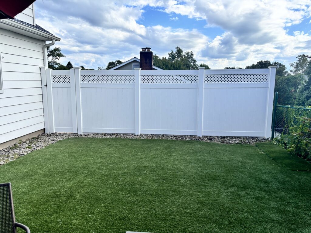 A white vinyl fence with a decorative lattice top installed in a backyard by Fence Factory Inc in Stamford, CT