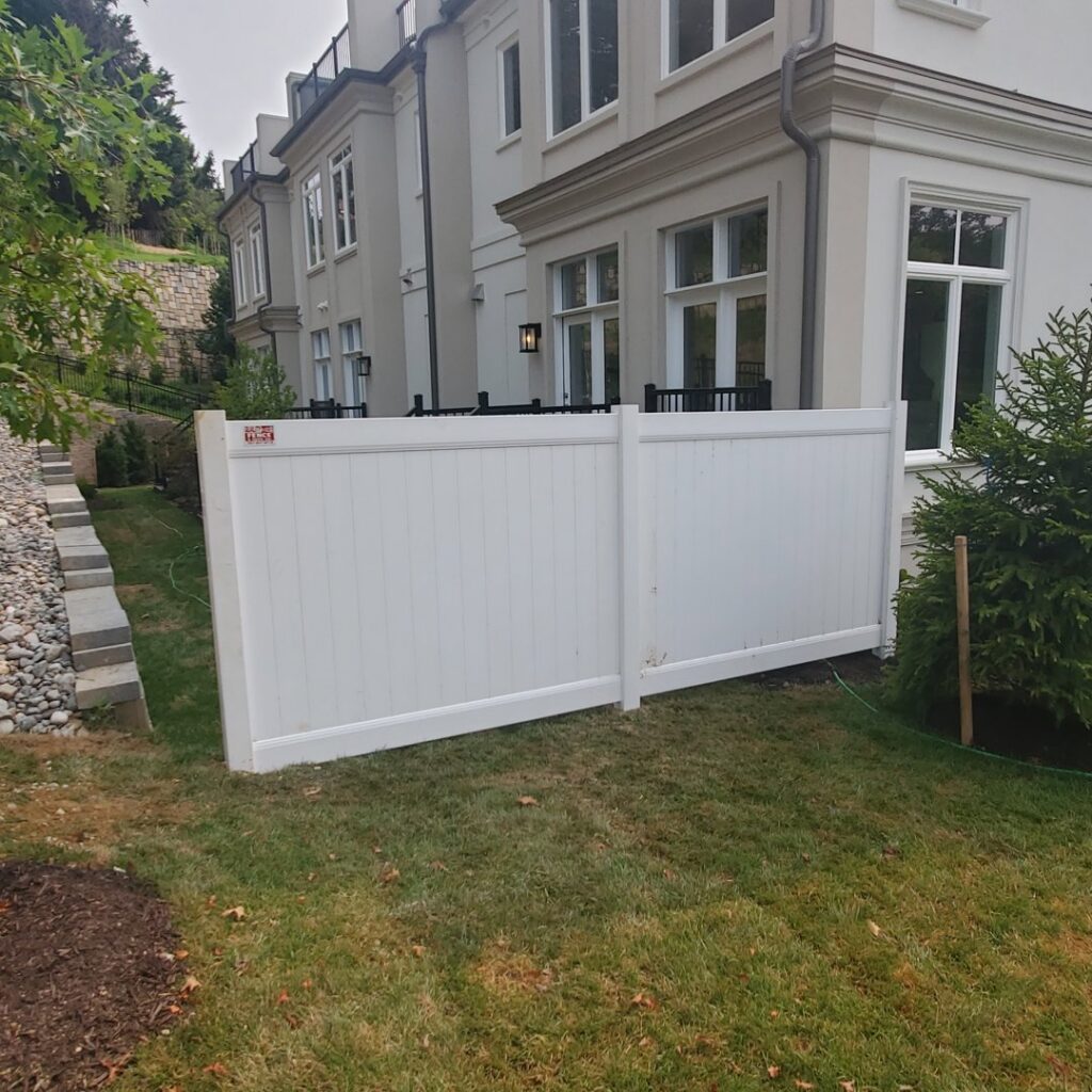 A white vinyl privacy fence installed next to a residential home by Quality Fence & Deck Co. in Frederick, MD.
