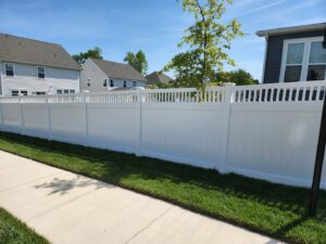 A long, newly installed white vinyl privacy fence along a sidewalk by Minors Fences in Ashland, VA.